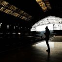 Lone passenger standing on an empty platform in a dark station
