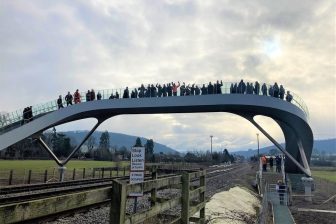 Crowd of people on experimental footbridge over rail tracks in England