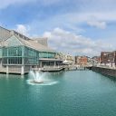 Image shot from out on the water of Prince's Quay in Hull showing glass fronted shopping centre and the old quayside