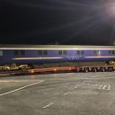 Night time picture of Caledonian Sleeper coach being delivered by road on a huge trailer