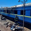 Firefighters stand in front of the carriage of a passenger train damaged in Kherson