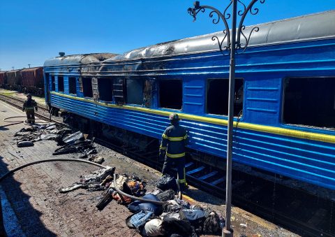 Firefighters stand in front of the carriage of a passenger train damaged in Kherson