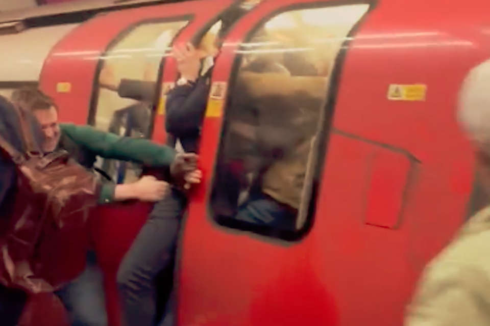Passengers on the platform attempting to force open the doors of a London Underground train to help passengers on board escape a possible fire