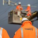 Engineers wearing Network Rail branded orange jackets work on overhead wires