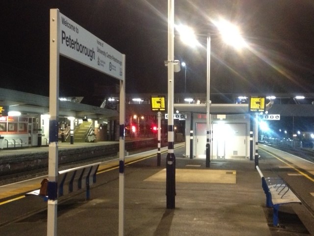 Peterborough station sign observed side on from the platform on a dark night 