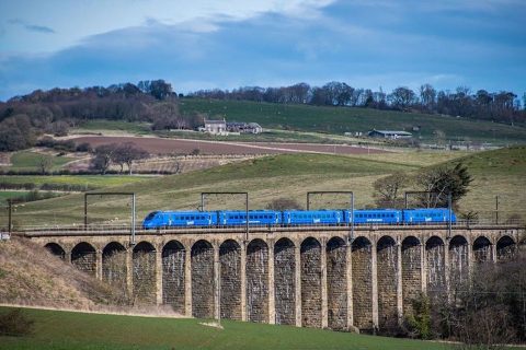 Blue liveried Lumo train of five cars on Lesbury Viaduct in Northumberland
