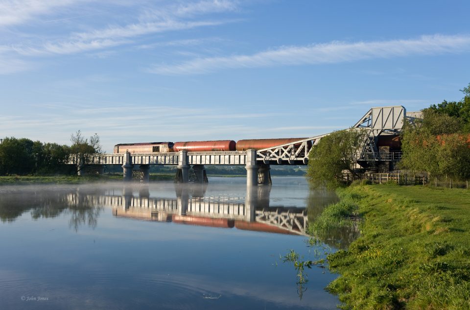 Freight train crosses a river bridge in Wales
