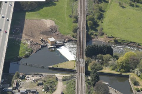 Overhead shot of River Devon Bridge at Newark showing double tracks and river below with a weir. There is a road to the left
