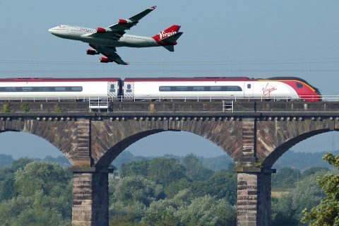 aircraft flying over a train which is on a viaduct