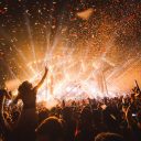 Night time view of music festival goers revelling in front of pyrotechnic display on stage