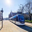 Edinburgh Tram at the platform in St Andrew Square with sun shining in a clear blue sky
