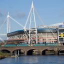 The Principality Stadium in Cardiff seen from the River Taff with a train passing in foreground