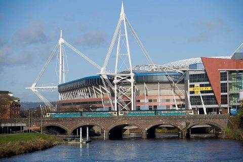 The Principality Stadium in Cardiff seen from the River Taff with a train passing in foreground