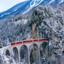 Aerial view of Train passing through famous mountain in Filisur, Switzerland. Landwasser Viaduct world heritage with train express in Swiss Alps snow winter scenery.