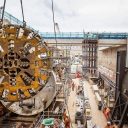 A tunnel boring machine cutting head is lowered into place in a trench