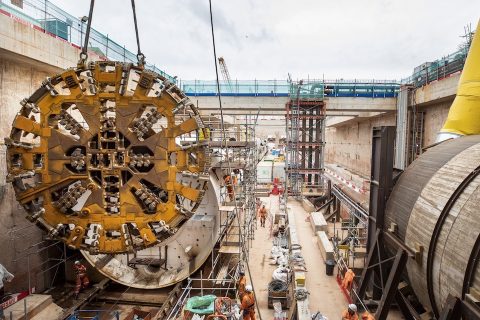 A tunnel boring machine cutting head is lowered into place in a trench